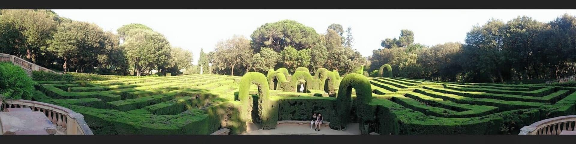 A formal garden with geometric hedges, a central statue, and a classical building.
