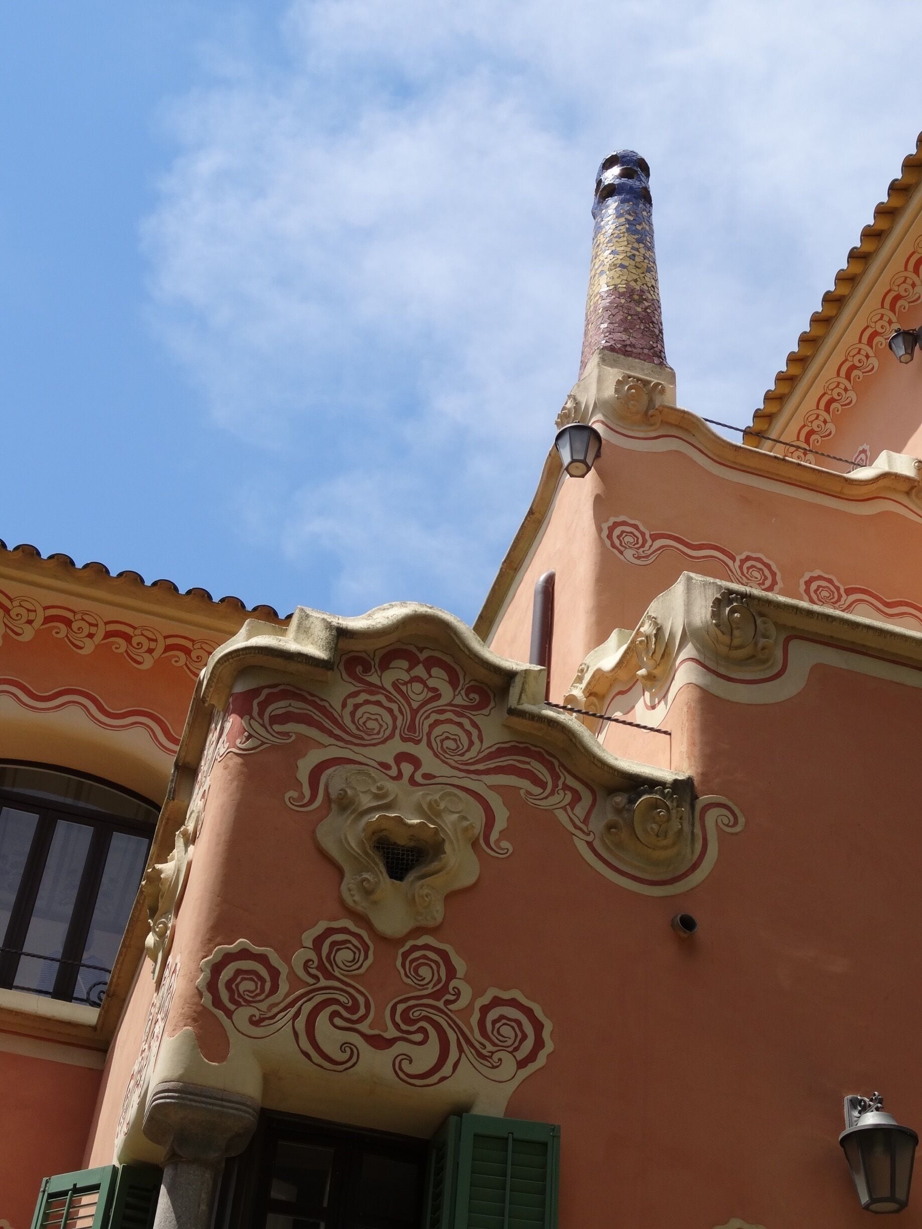 Ein Gebäude mit aufwendigen architektonischen Details, darunter ein Zierkamin und filigrane Muster an der Fassade.
