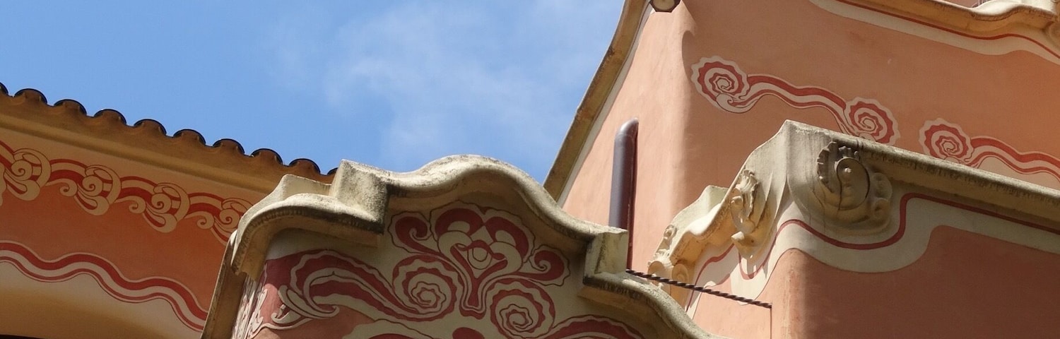 Um edifício com detalhes arquitetônicos elaborados, incluindo uma chaminé decorativa e padrões intrincados na fachada.