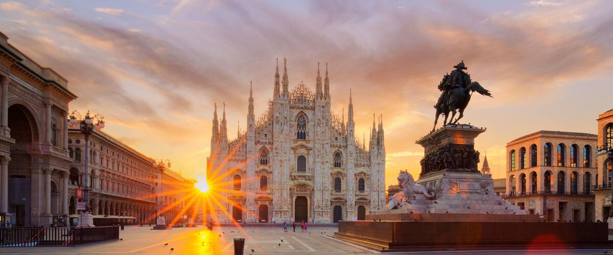 A grand cathedral with intricate Gothic architecture, a statue of a historical figure, and a bustling square with people and pigeons.