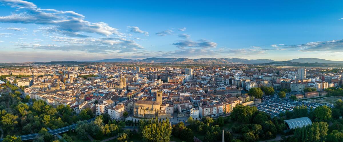 A panoramic view of a city with a river, bridges, and mountains in the background.
