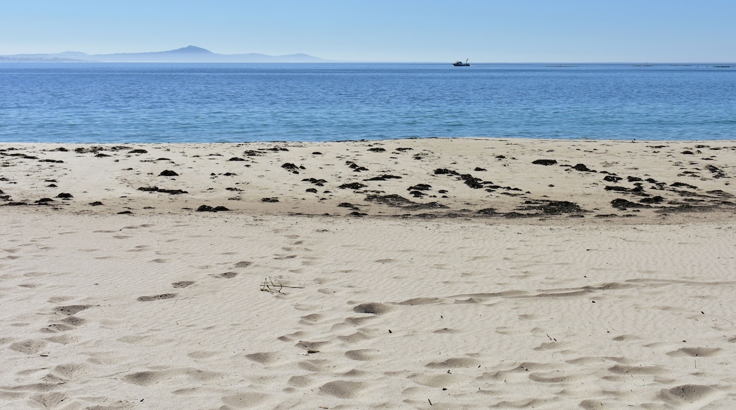 Beach with fishing boat, blue sea and mist. Sunny day, Galicia, Spain.