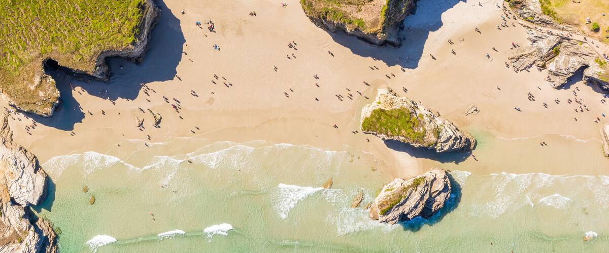 A coastal landscape with clear turquoise waters, sandy beaches, and rocky outcrops.