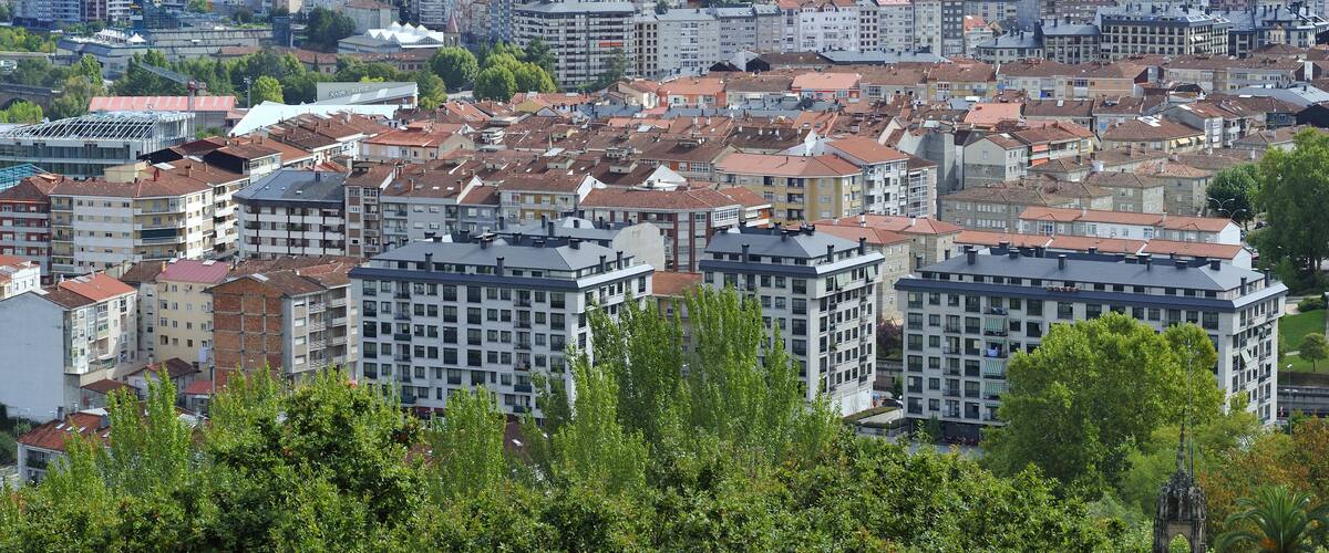 A cityscape with dense urban buildings, a prominent church, and a mountainous backdrop.