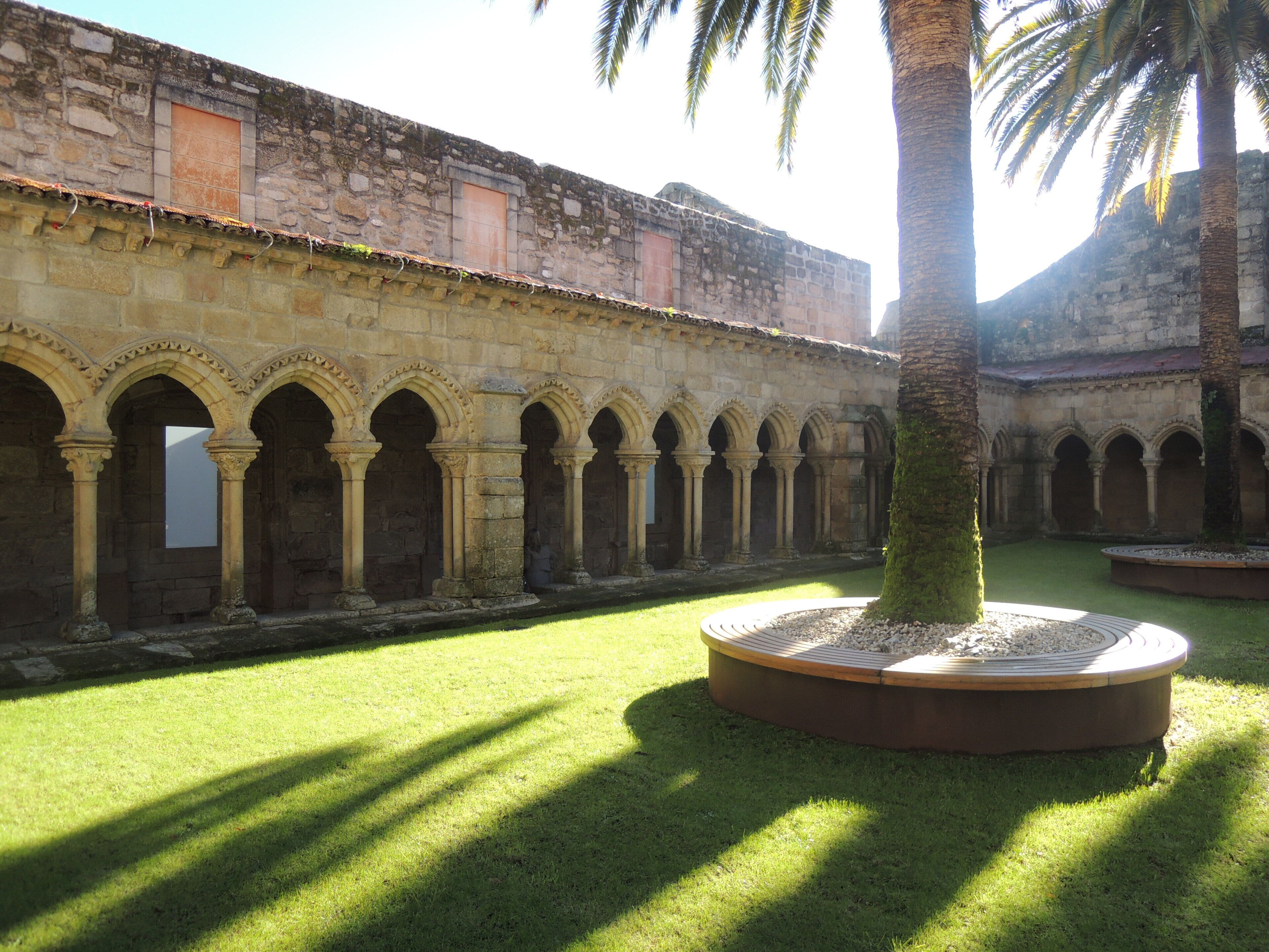 A courtyard with stone arches, a palm tree, and a well-maintained lawn.