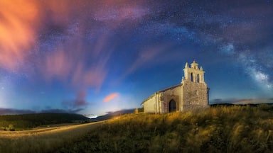 Una iglesia con un campanario bajo un cielo nocturno estrellado.