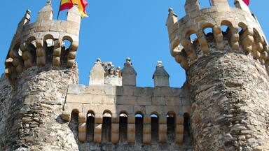 A historic stone castle with crenellated towers and flags.