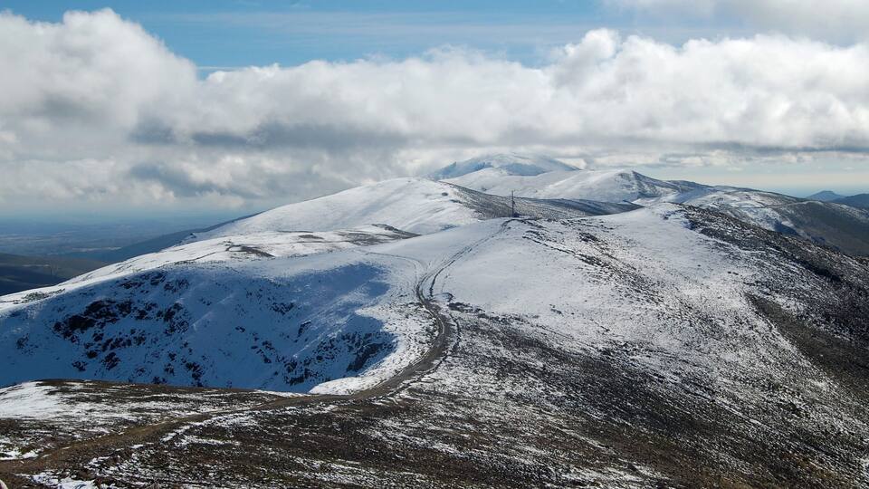 A snow-covered mountain with a clear sky and clouds.