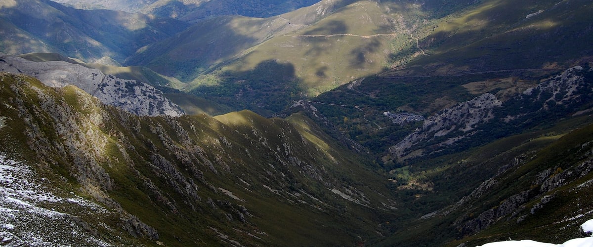 A mountainous landscape with valleys and distant smoke plumes.