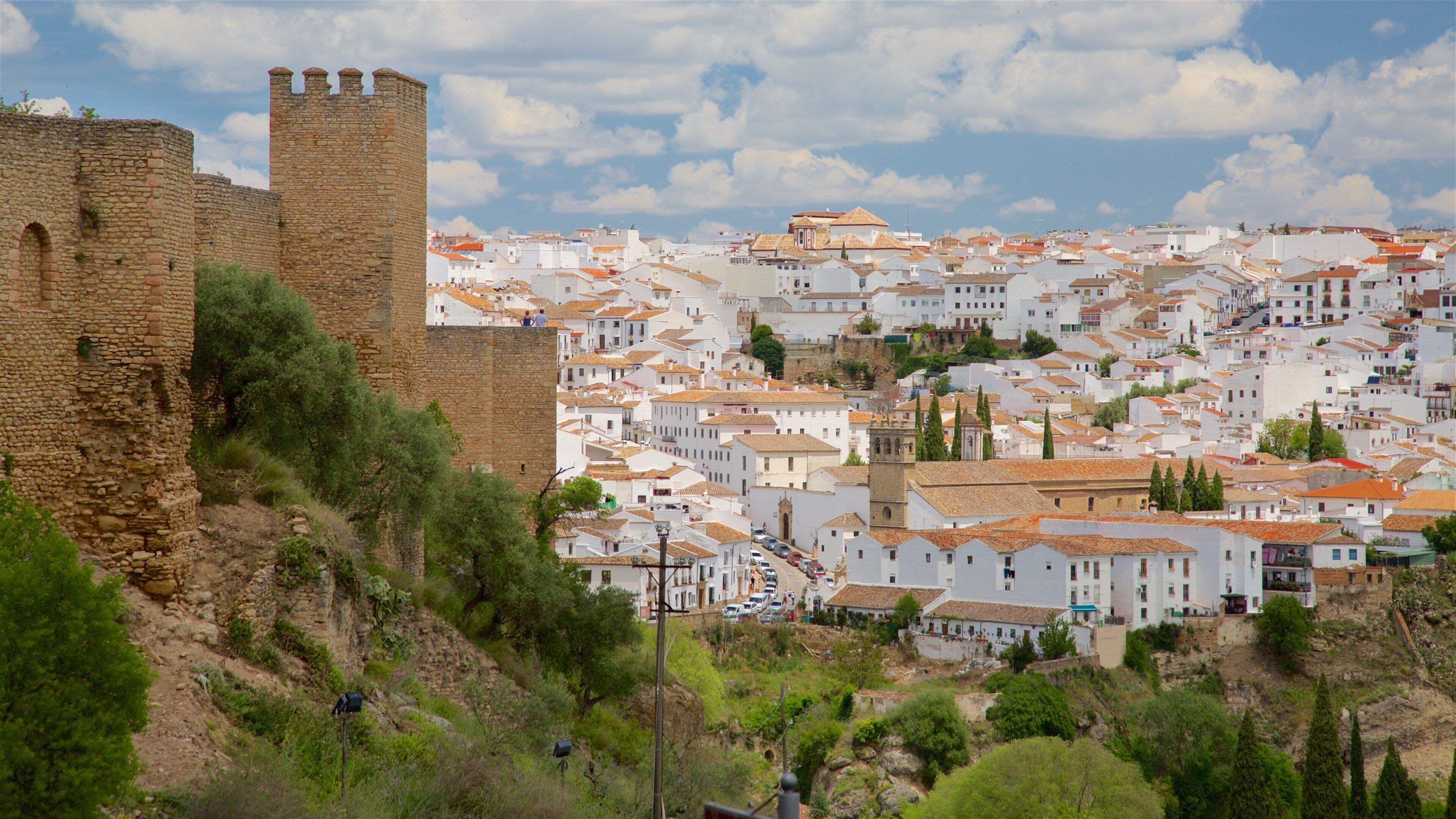 A historic stone tower and a densely packed town with white buildings and terracotta roofs.