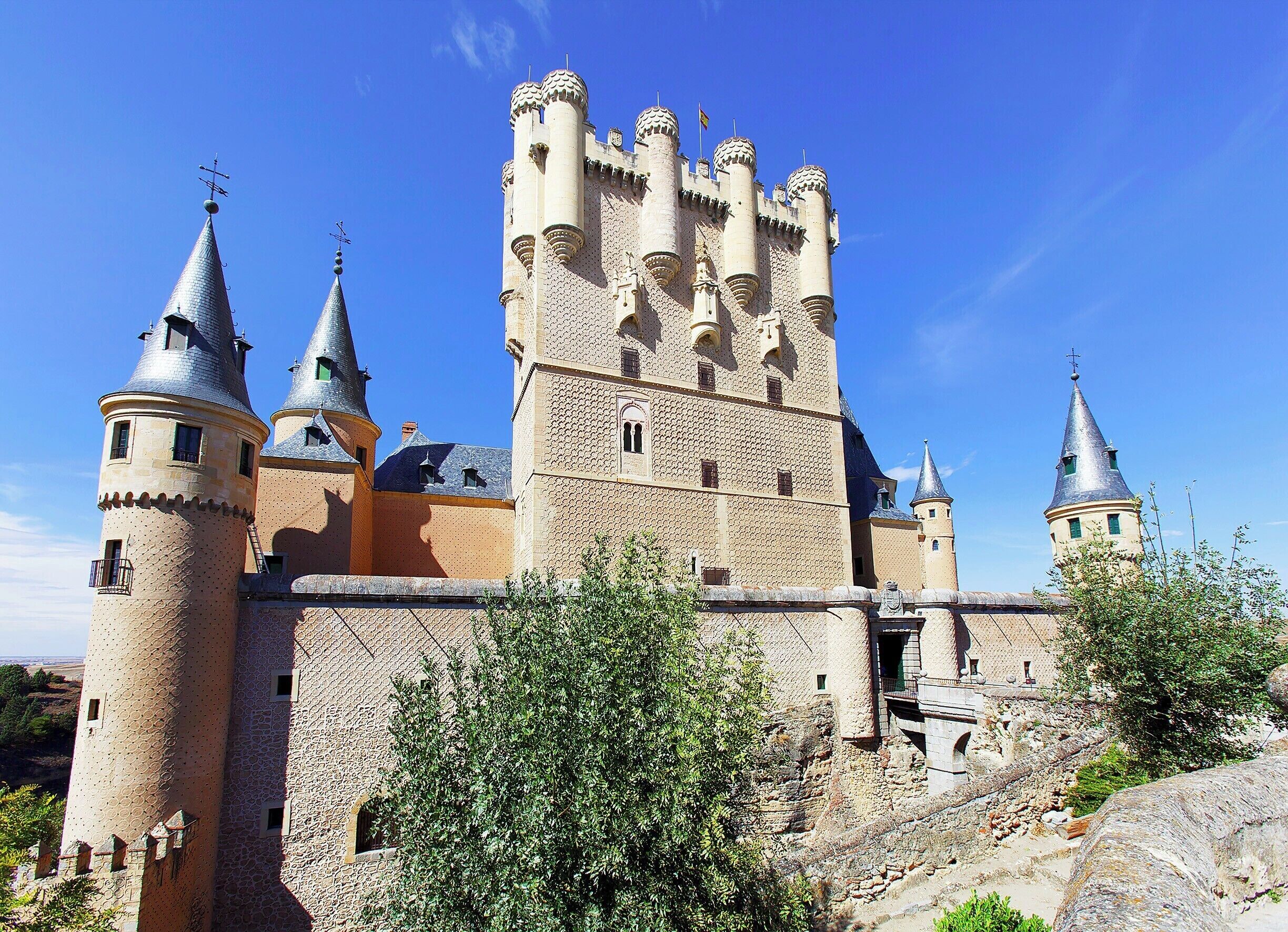 Segovia's castle sits like the bow of a ship at the northwest tip of the city.  It's a massive, imposing structure that was added to over many generations.  Pictured here is the side of the castle facing the city.  The tall, awkward-looking tower in the middle was added by King John II in the early 15th century.  

The true beauty of the castle, though, lies with it's interior rooms, which were handcrafted by Arabian workmen (under Christian rule) in the early 14th-century.  The attention to detail and the scale of the works rival those found at the Alhambra and the Alcázar of Seville.  Well worth the entry fee just to wander the rooms.
