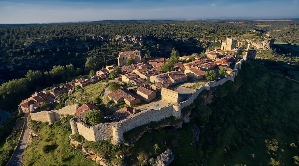 A medieval town with a stone wall and buildings with red-tiled roofs.