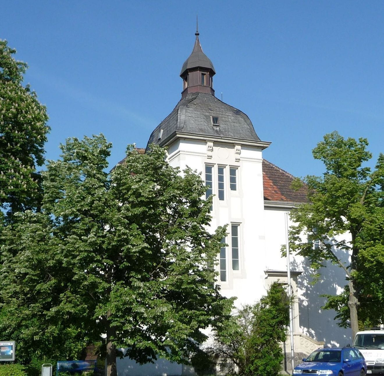 A white church with a pointed steeple and a red-tiled roof.