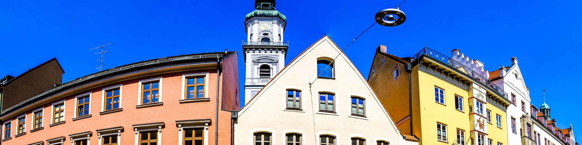 A row of colorful buildings with a prominent clock tower in the background.