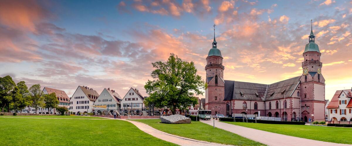 A historic church with twin towers and a surrounding town square with traditional buildings.