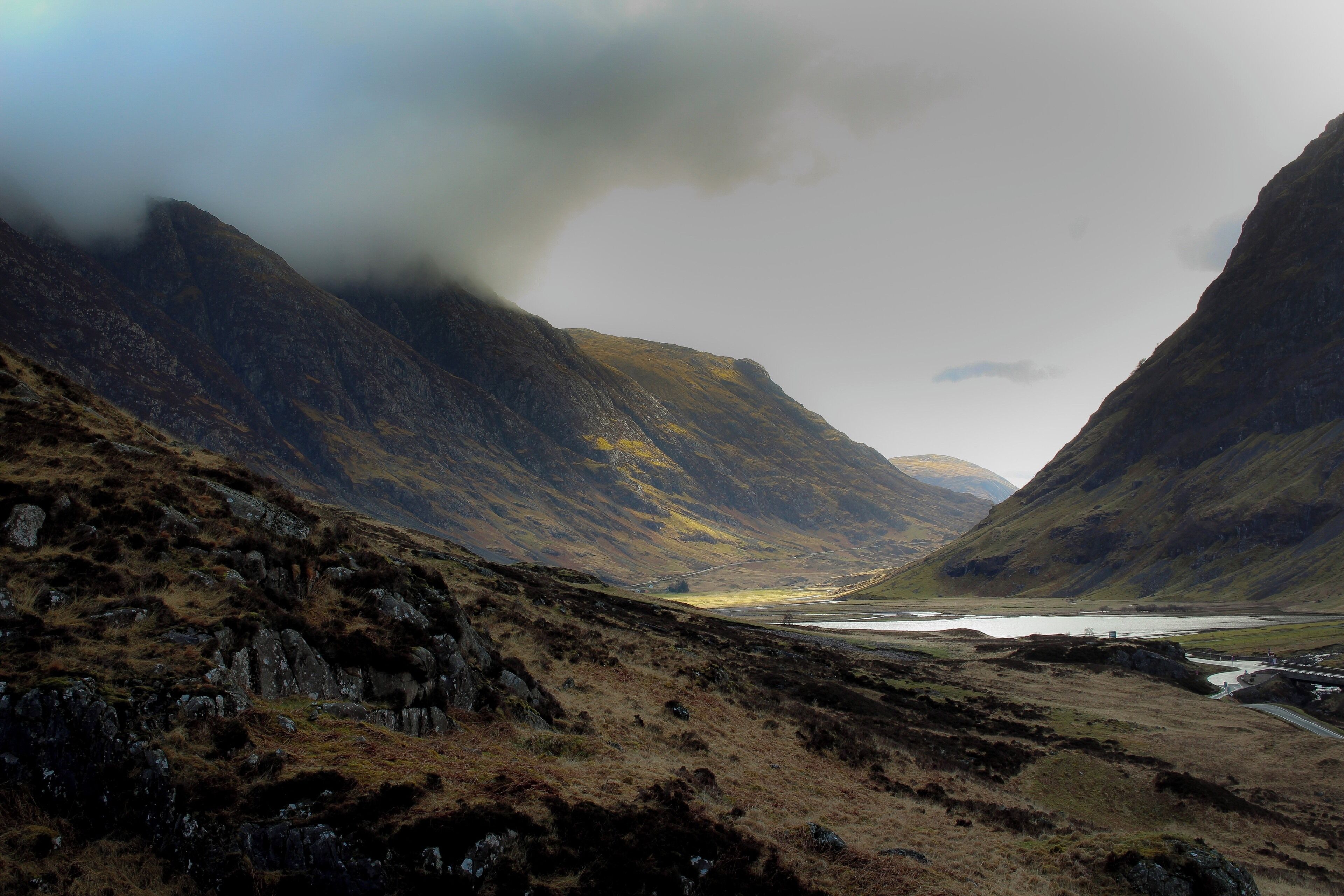 A mountainous landscape with a valley, a river, and a bridge.