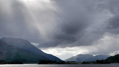 A mountainous landscape with a lake and overcast skies.