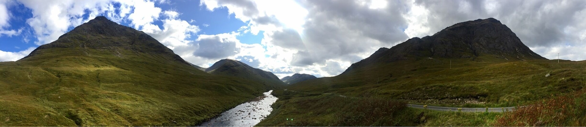 Un paisaje montañoso con un río que atraviesa un valle, una carretera sinuosa y una línea eléctrica.