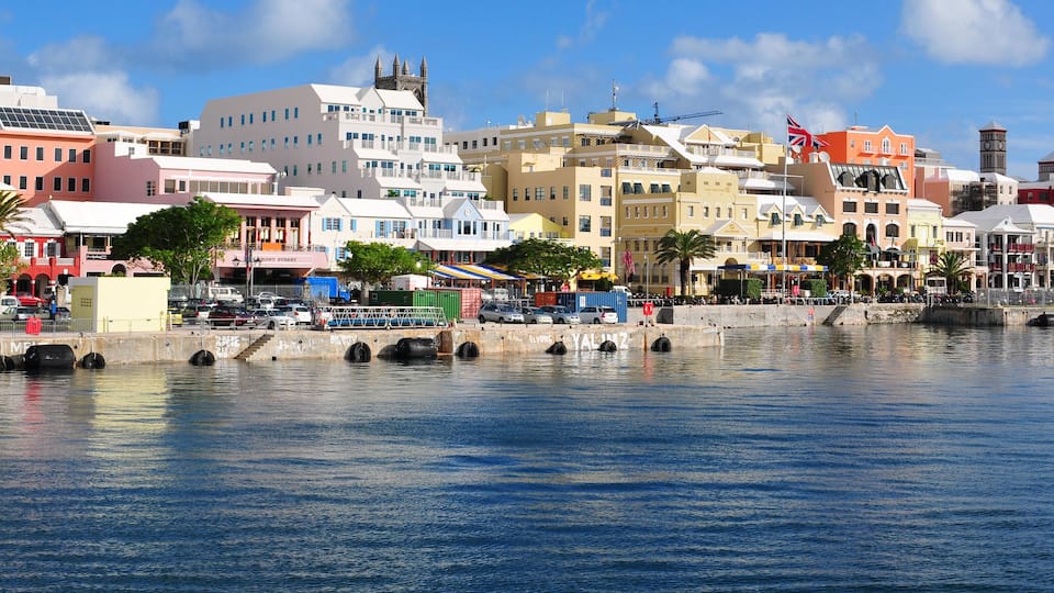 A waterfront cityscape with colorful buildings, a bridge, and a clock tower.
