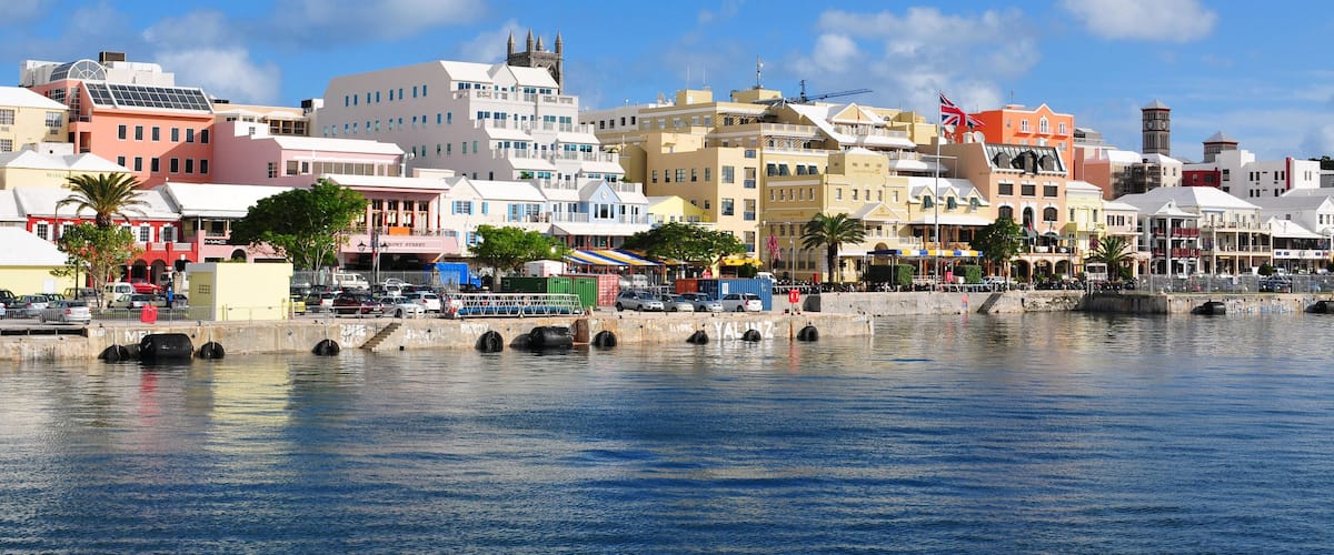 A waterfront cityscape with colorful buildings, a bridge, and a clock tower.