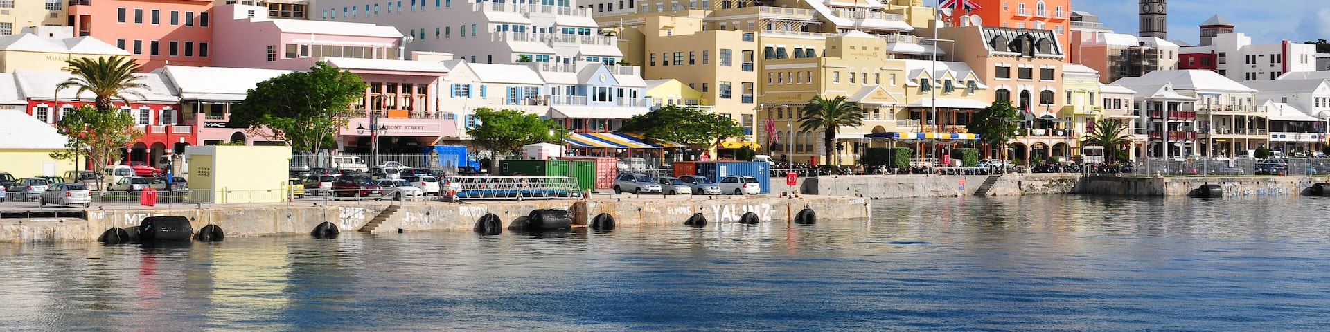 A waterfront cityscape with colorful buildings, a bridge, and a clock tower.
