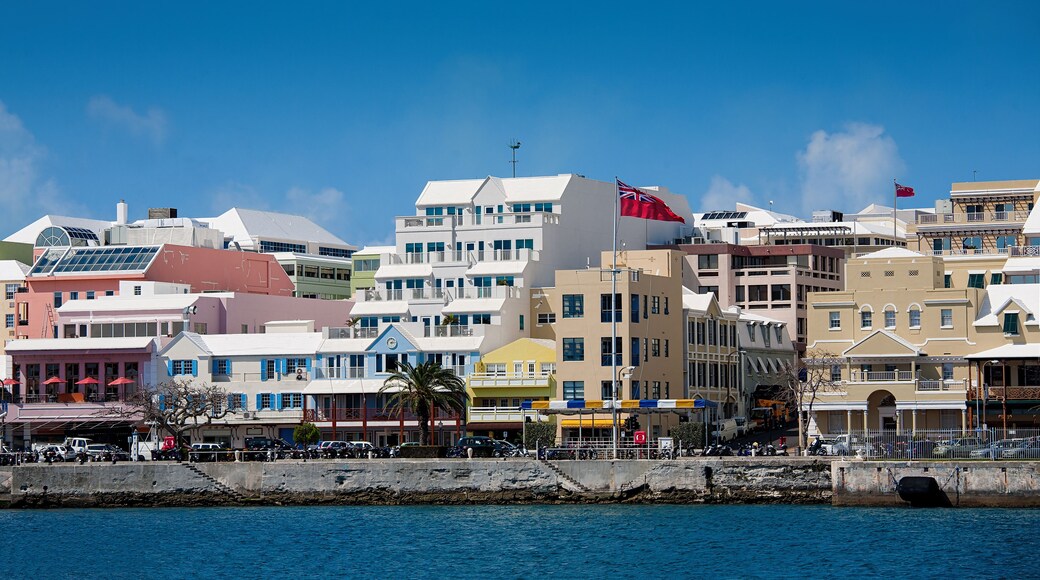 A coastal cityscape with colorful buildings, a clear blue sky, and a calm sea.