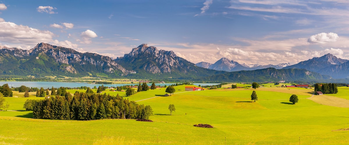 A mountainous landscape with a lake, green fields, and scattered buildings.
