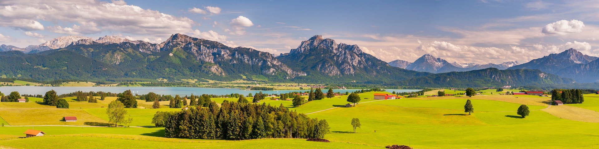 A mountainous landscape with a lake, green fields, and scattered buildings.