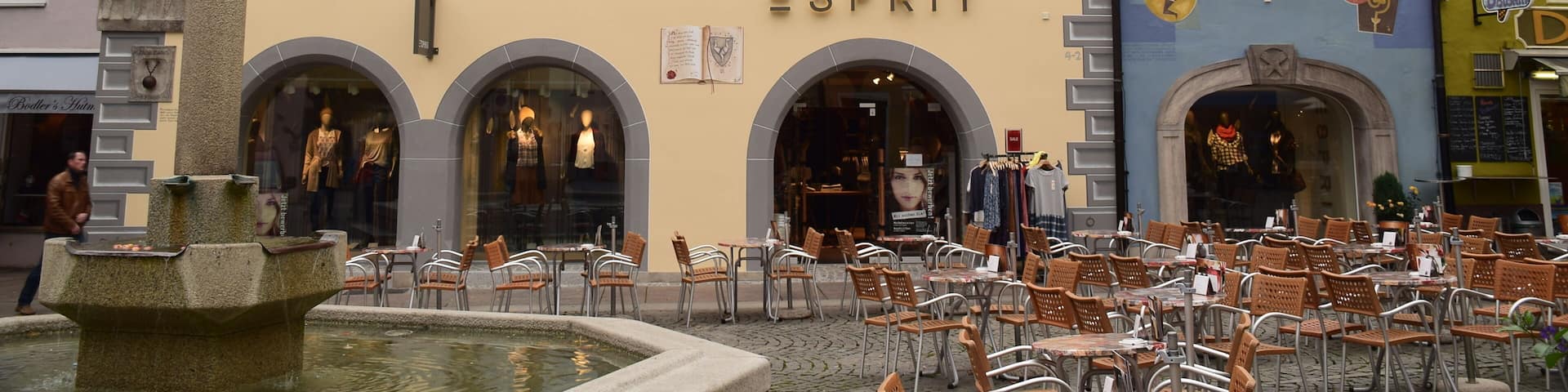 A building with the sign 'ESPRIT' and a statue of a man on a pillar.