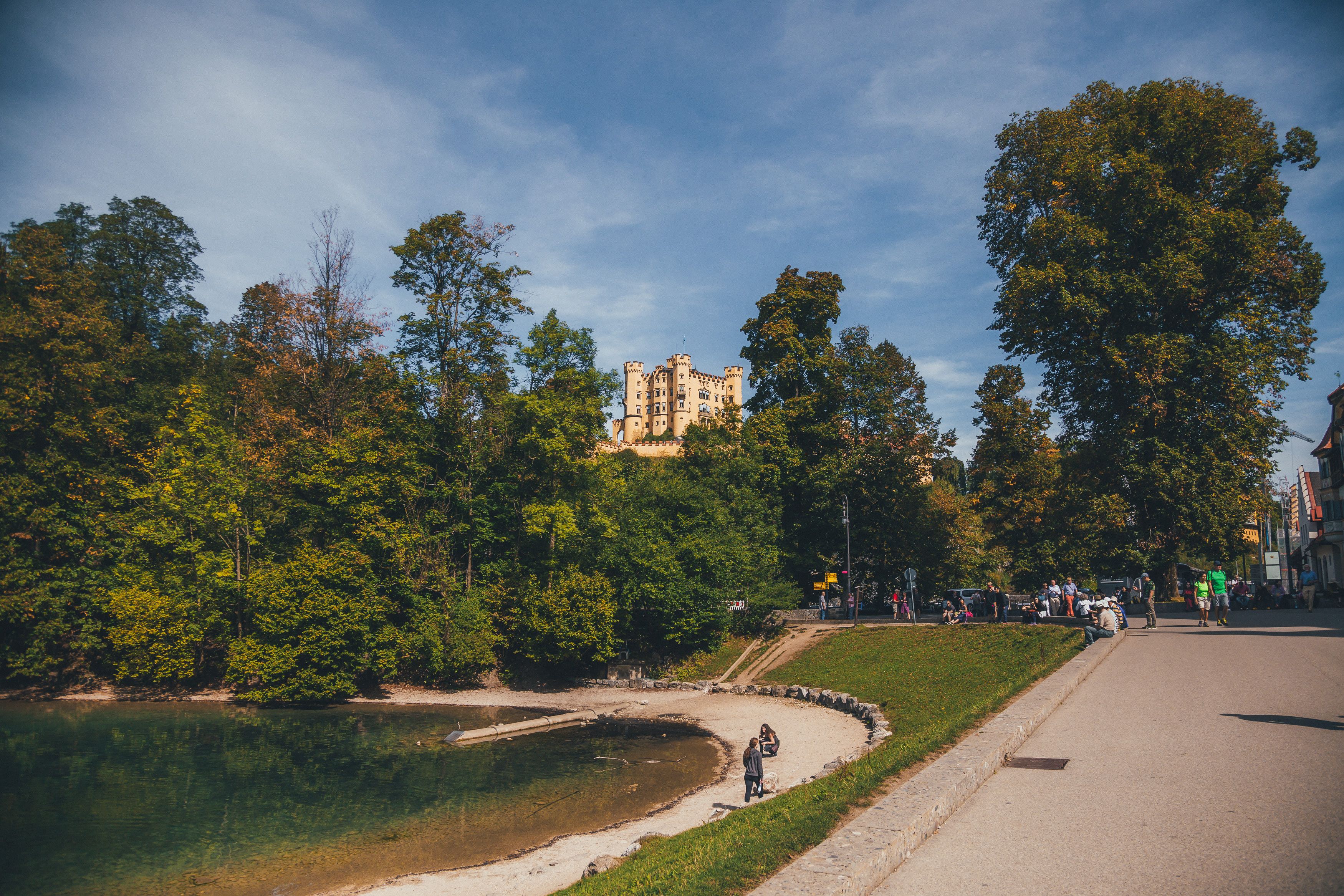Un parque con un castillo al fondo, un sendero curvo y una masa de agua.