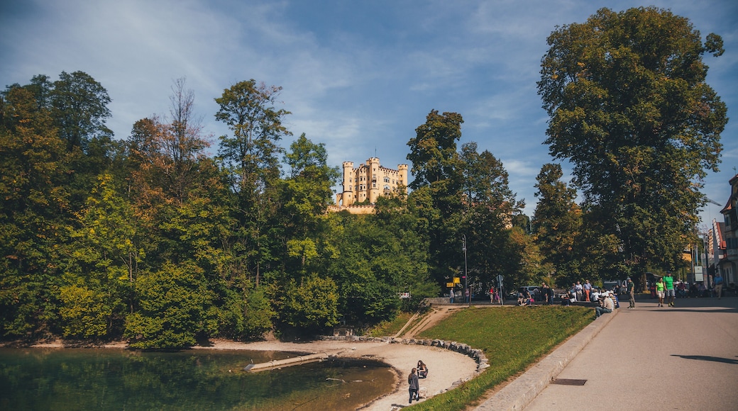 Un parque con un castillo al fondo, un sendero curvo y una masa de agua.
