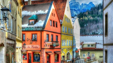 Una calle colorida con una tienda llamada "Haus der Kinder" y un letrero que dice "Indes".