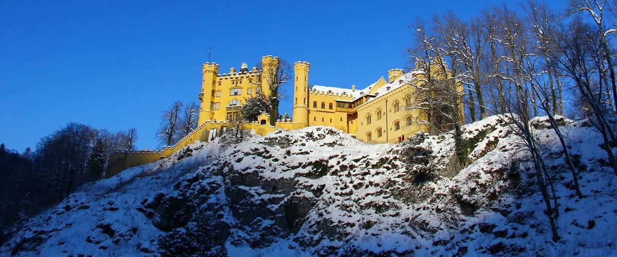 A snow-covered castle on a hill with a clear blue sky.
