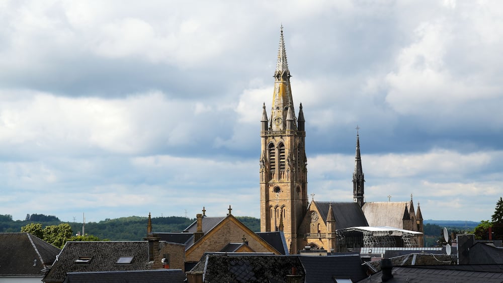 church of arlon over the roofs of the old town against a cloudy sky with copy space, belgium, europe