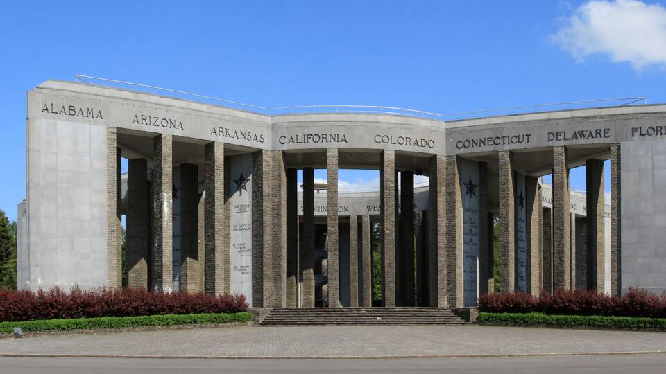 A monument with columns labeled with state names and military branches.