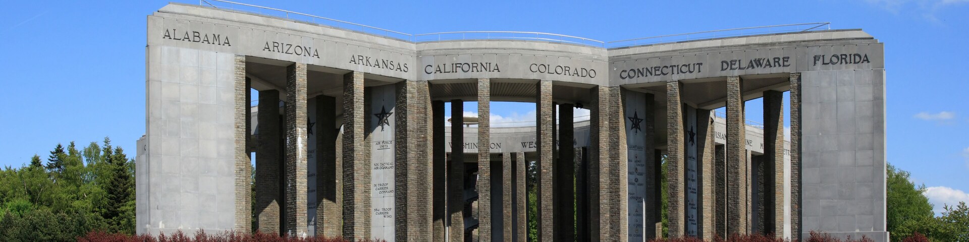A monument with columns labeled with state names and military branches.