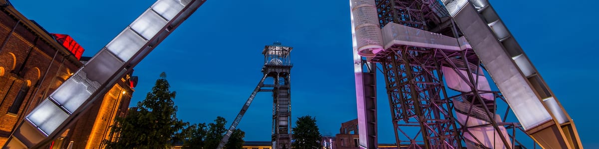 A tall, metallic structure with a sloped roof, likely a part of an amusement park ride, set against a twilight sky.