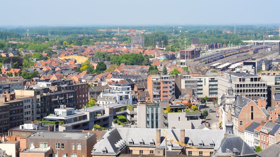 A cityscape with a mix of modern and traditional architecture, a train station, and a distant view of a bridge.
