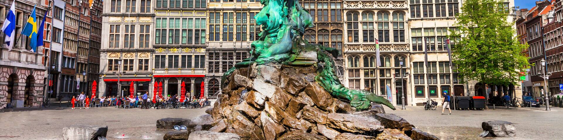 A statue of a woman in a dynamic pose, a fountain, and historic buildings with intricate architecture.