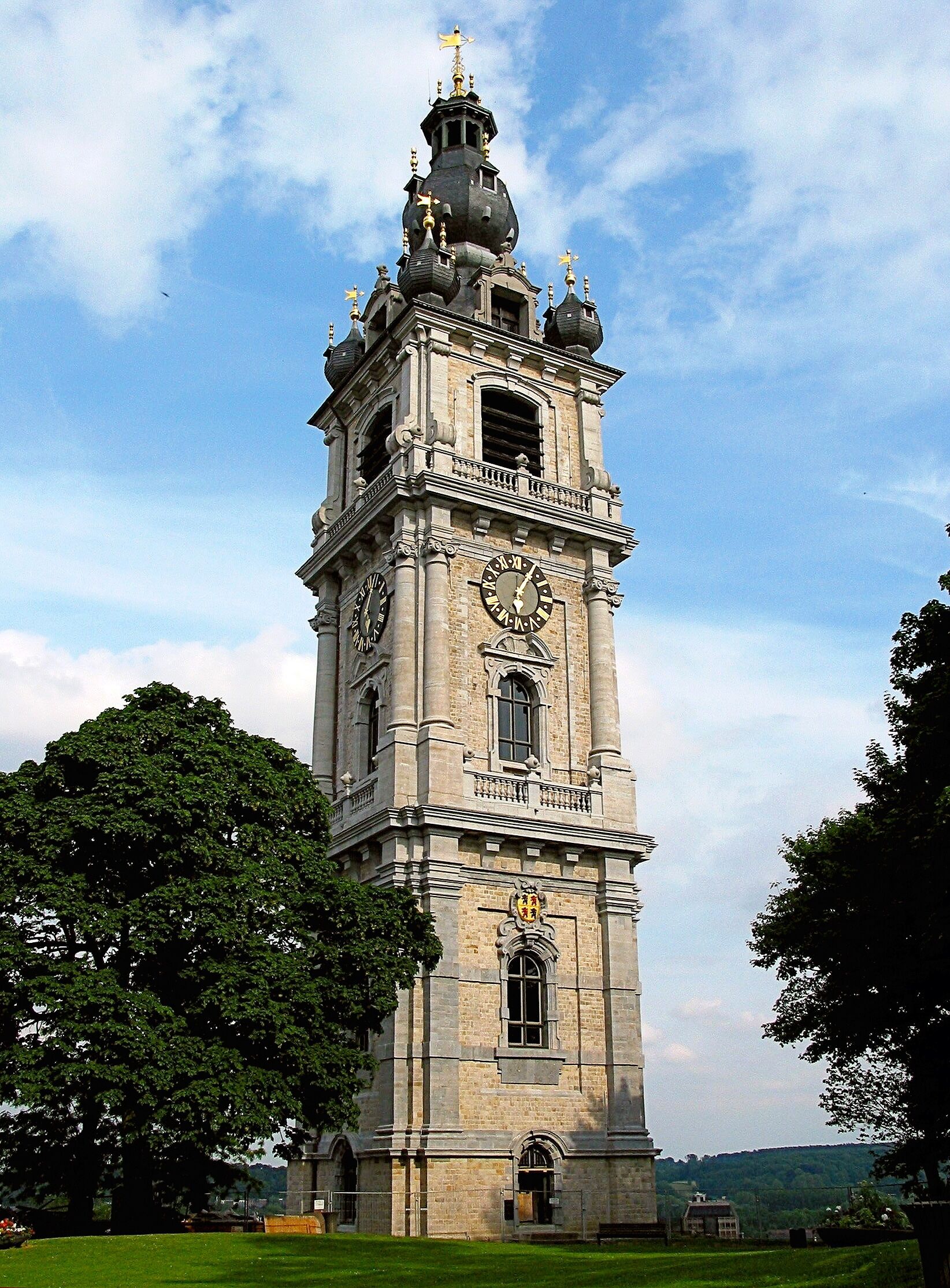 A historic clock tower with a dome and spire, surrounded by trees.
