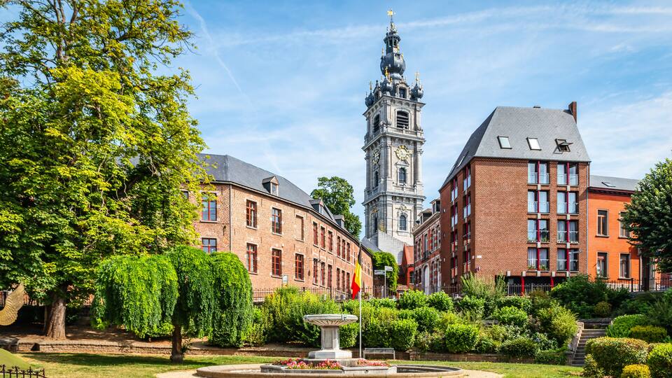 A historic building with a clock tower, surrounded by lush greenery and a well-maintained garden.