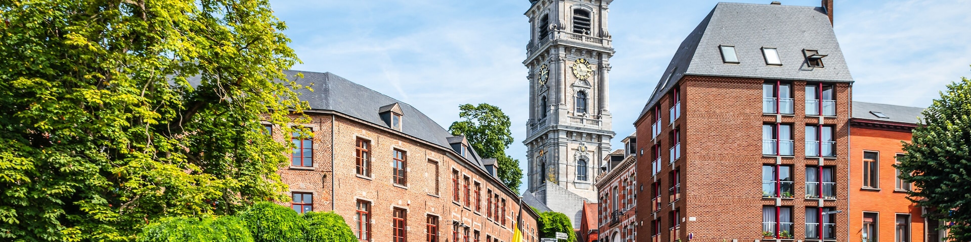 A historic building with a clock tower, surrounded by lush greenery and a well-maintained garden.
