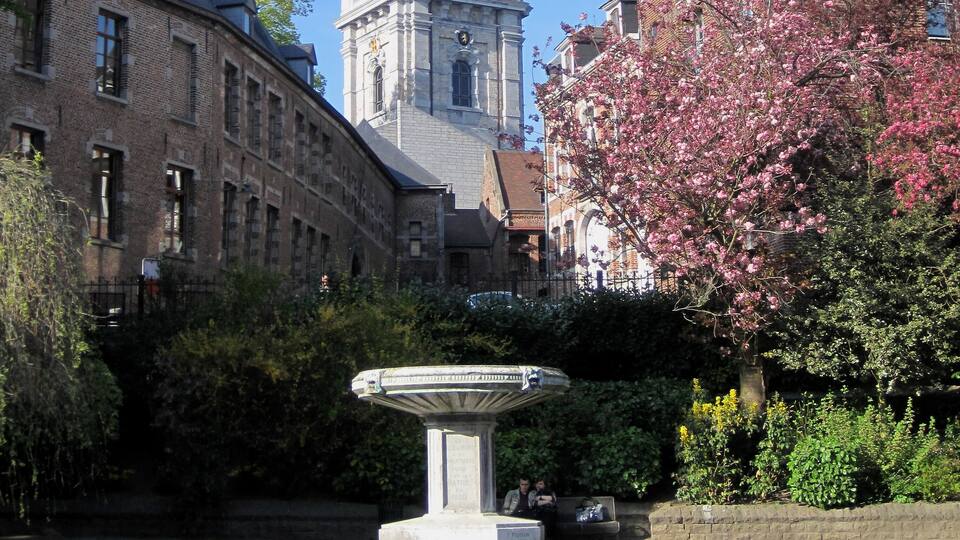 A historic clock tower, a fountain, and a building with a brick facade.