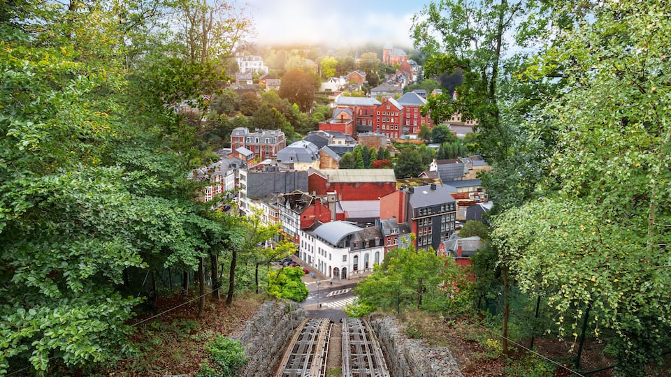 A town with red and white buildings, surrounded by dense green trees.
