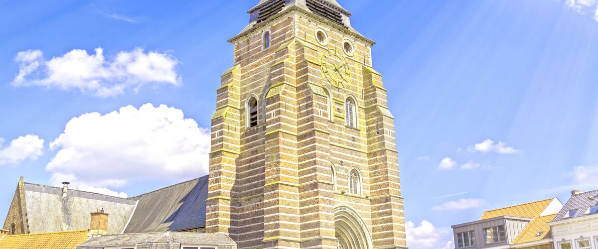 A historic tower with a pointed roof and a weather vane, surrounded by traditional buildings with gabled roofs.