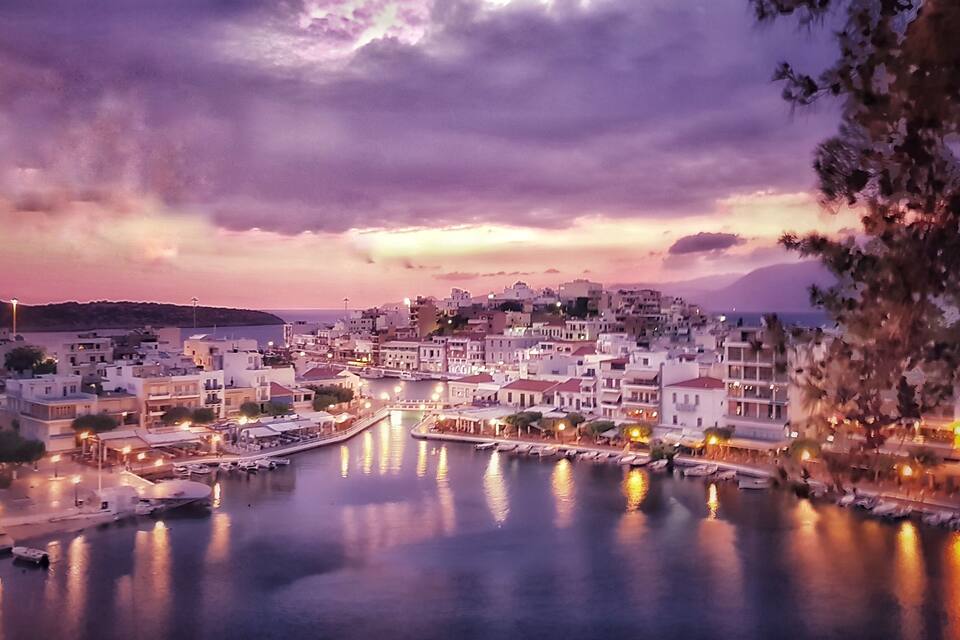 Un pueblo costero al atardecer, con edificios a lo largo de la costa y un mar en calma.
