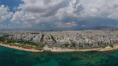 Vista aérea de uma cidade costeira, com área urbana densa, praia e águas azul-claras.
