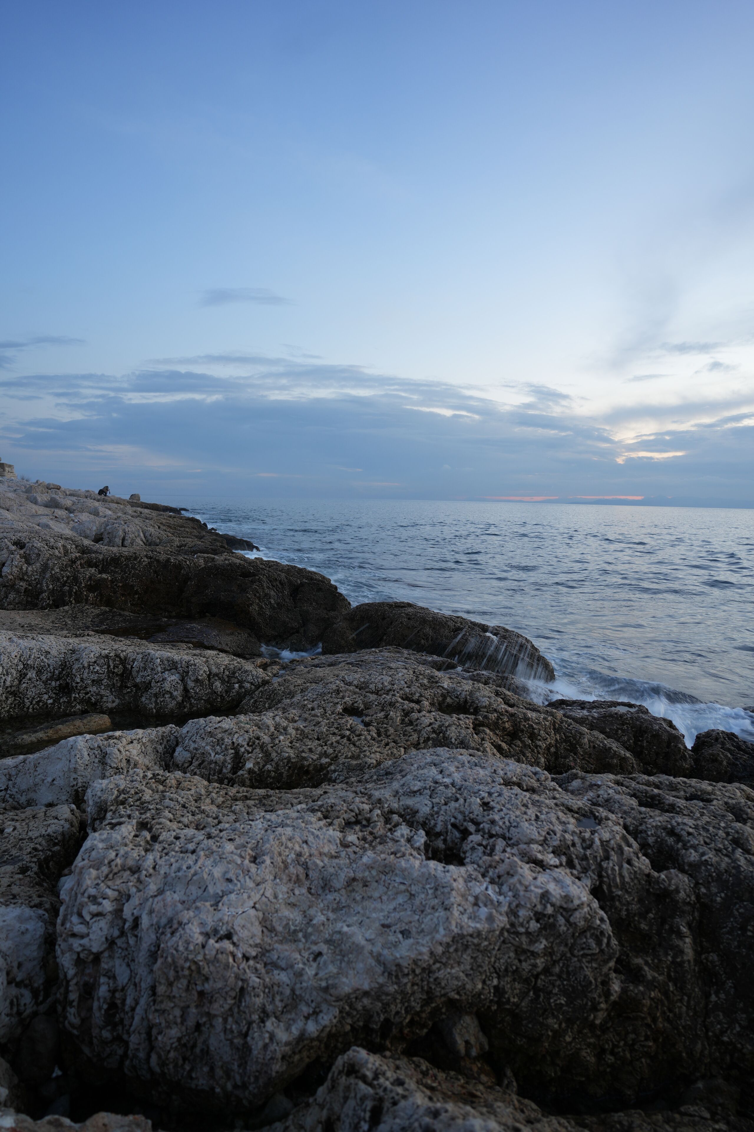 Beautiful shot of a sea with waves crashing on the rocks during the sunset in Pireas, Greece