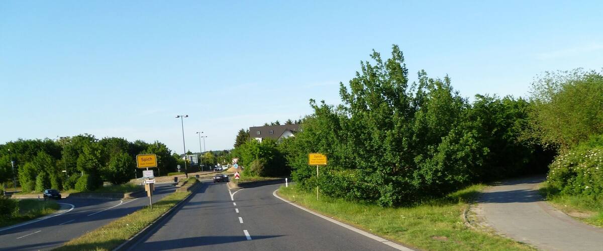A two-lane road with a curve, surrounded by greenery and trees.