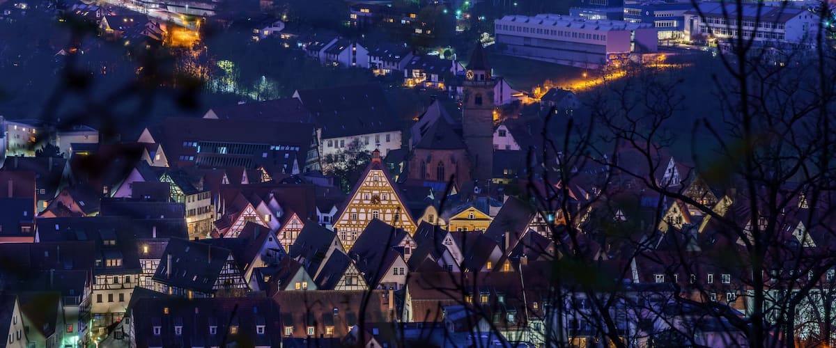 A town at night with illuminated buildings and a prominent church steeple.